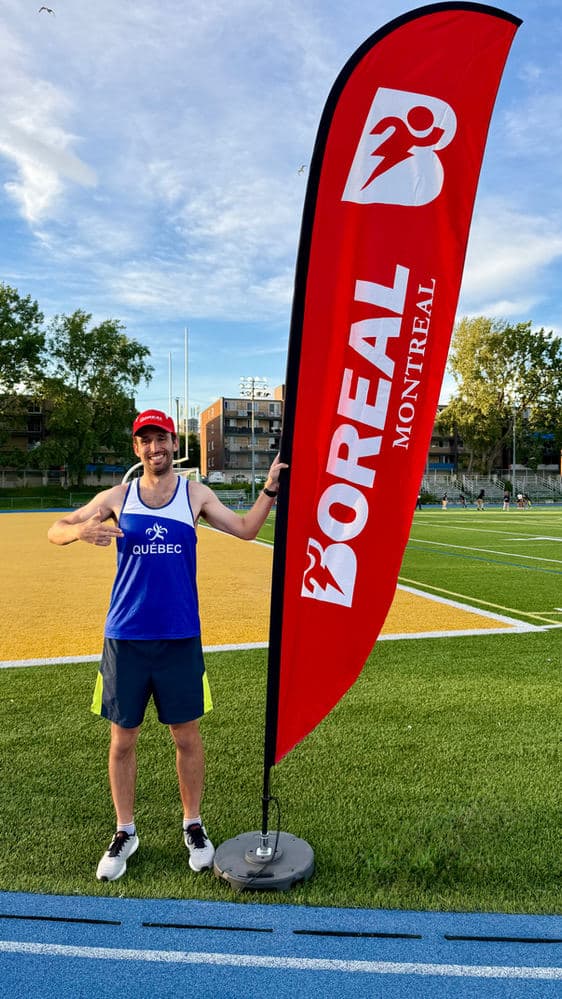 François Jarry, in a Team Québec singlet, on a track next to a Boréal banner.