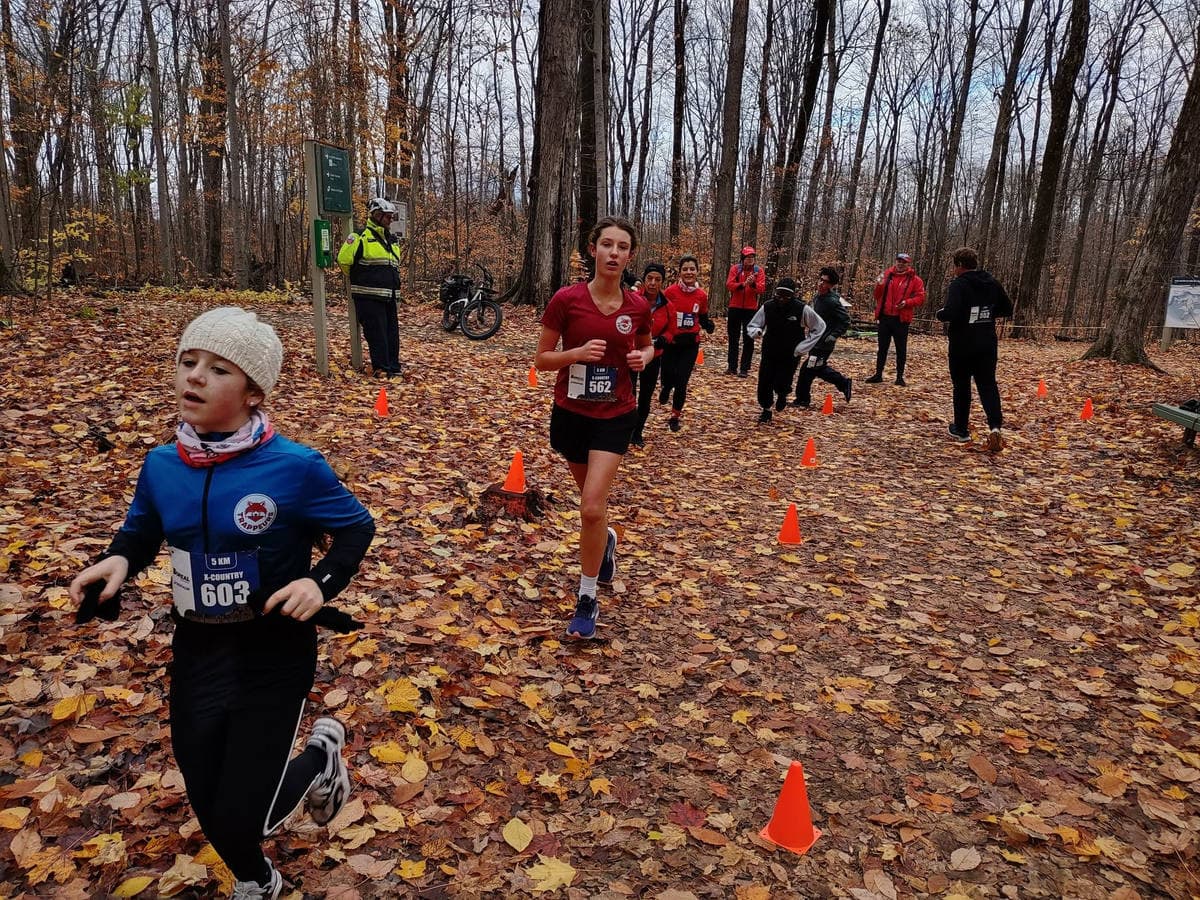 Young runners on a trail covered in fallen leaves.