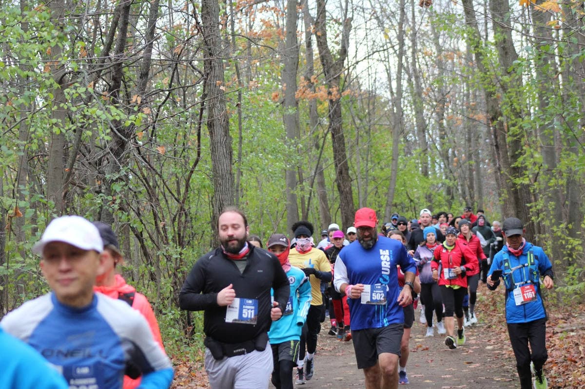 Runners wearing race bibs on a trail in the nature park.