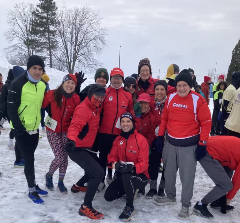 Boreal club members in winter jackets, gathered in the snow after a run.